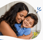 Smiling woman with long dark hair hugs a young boy in a blue polo shirt.